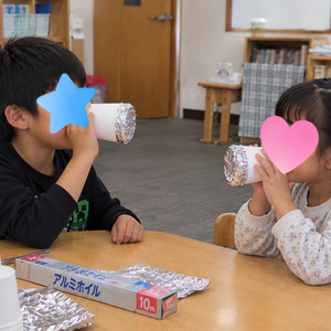 アルミホイル電話で遊ぶ教室の子どもたち