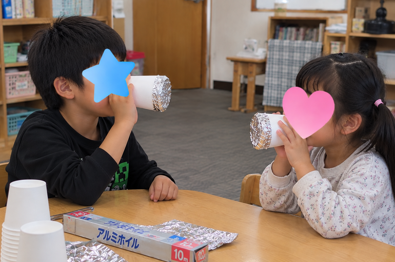 アルミホイル電話で遊ぶ教室の子どもたち